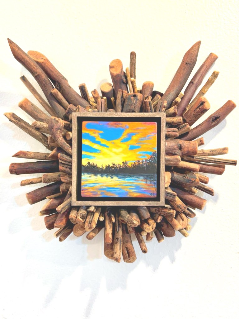 Small painting of colorful sunset with a frame sticks radiating out by Jeanetta Darley ARTIST